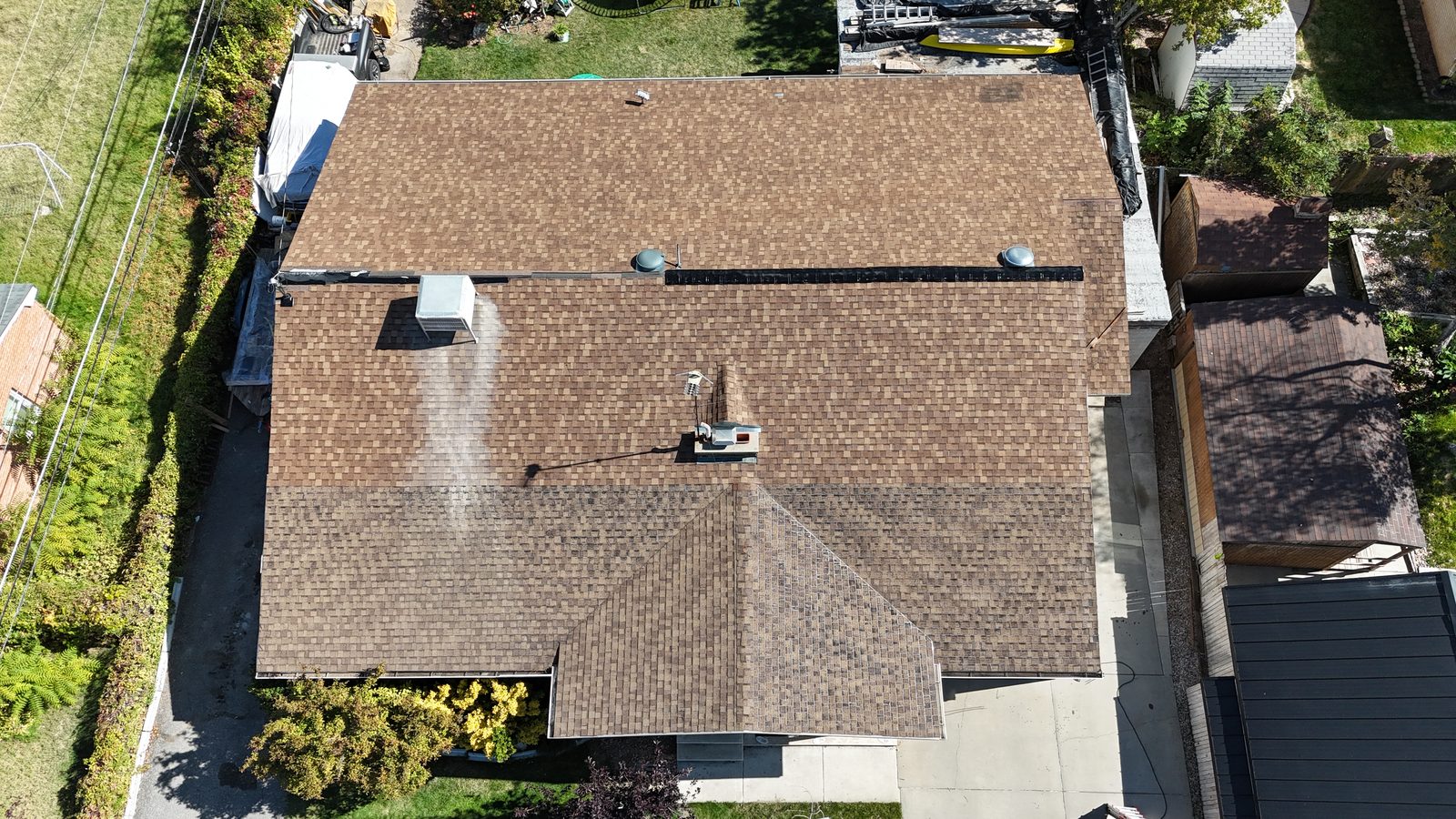 The same roof from overhead later that day, the main roof visibly darker after treatment.