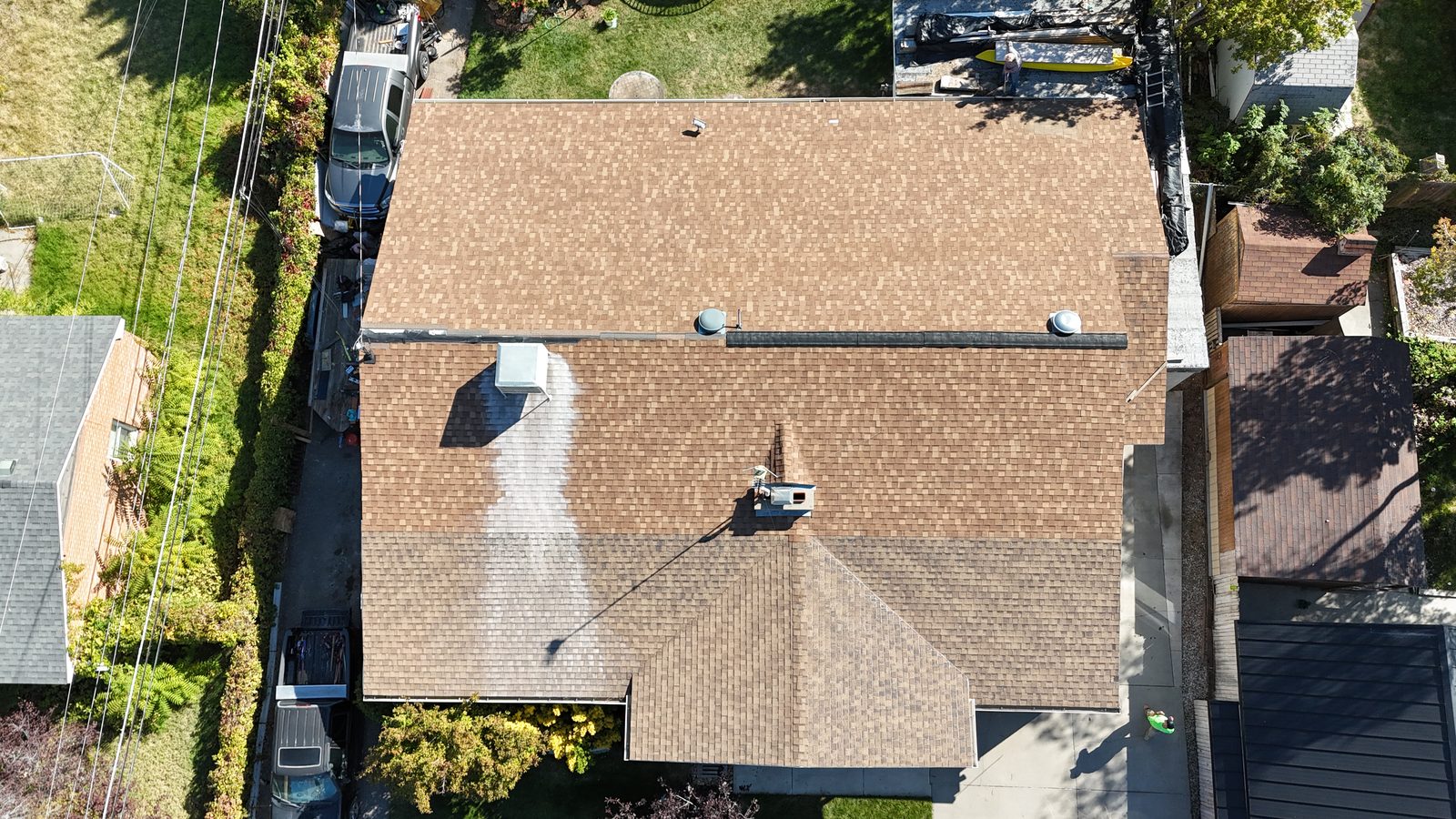 Overhead view of a single-storey home's tan asphalt shingle roof before treatment.